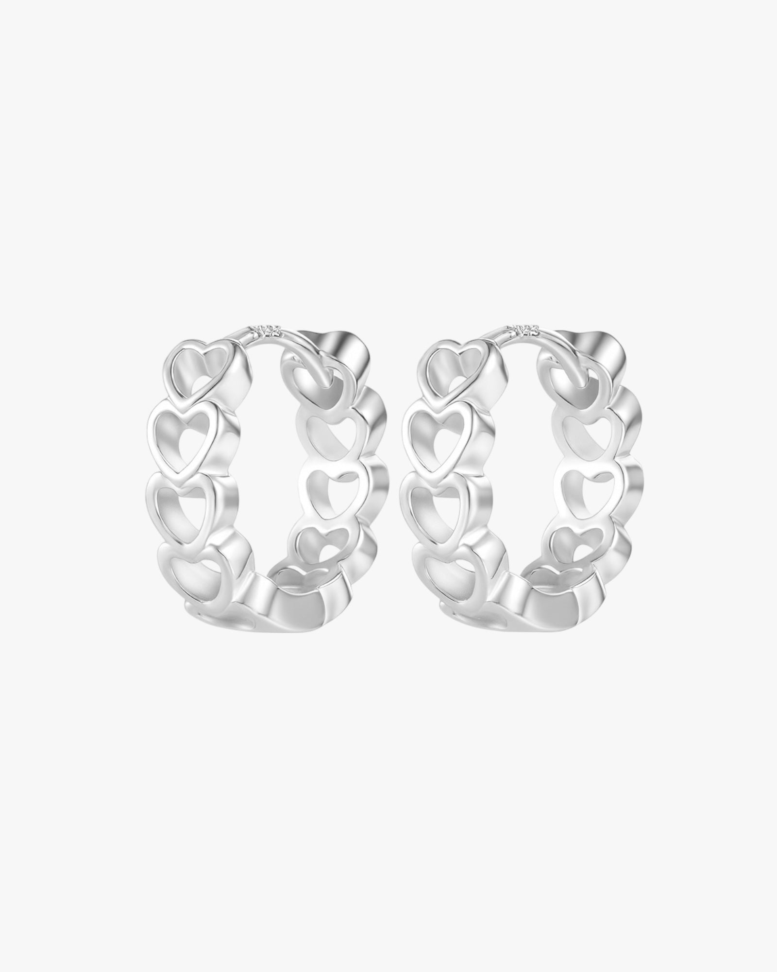 Silver hoop earrings with heart designs on a white background