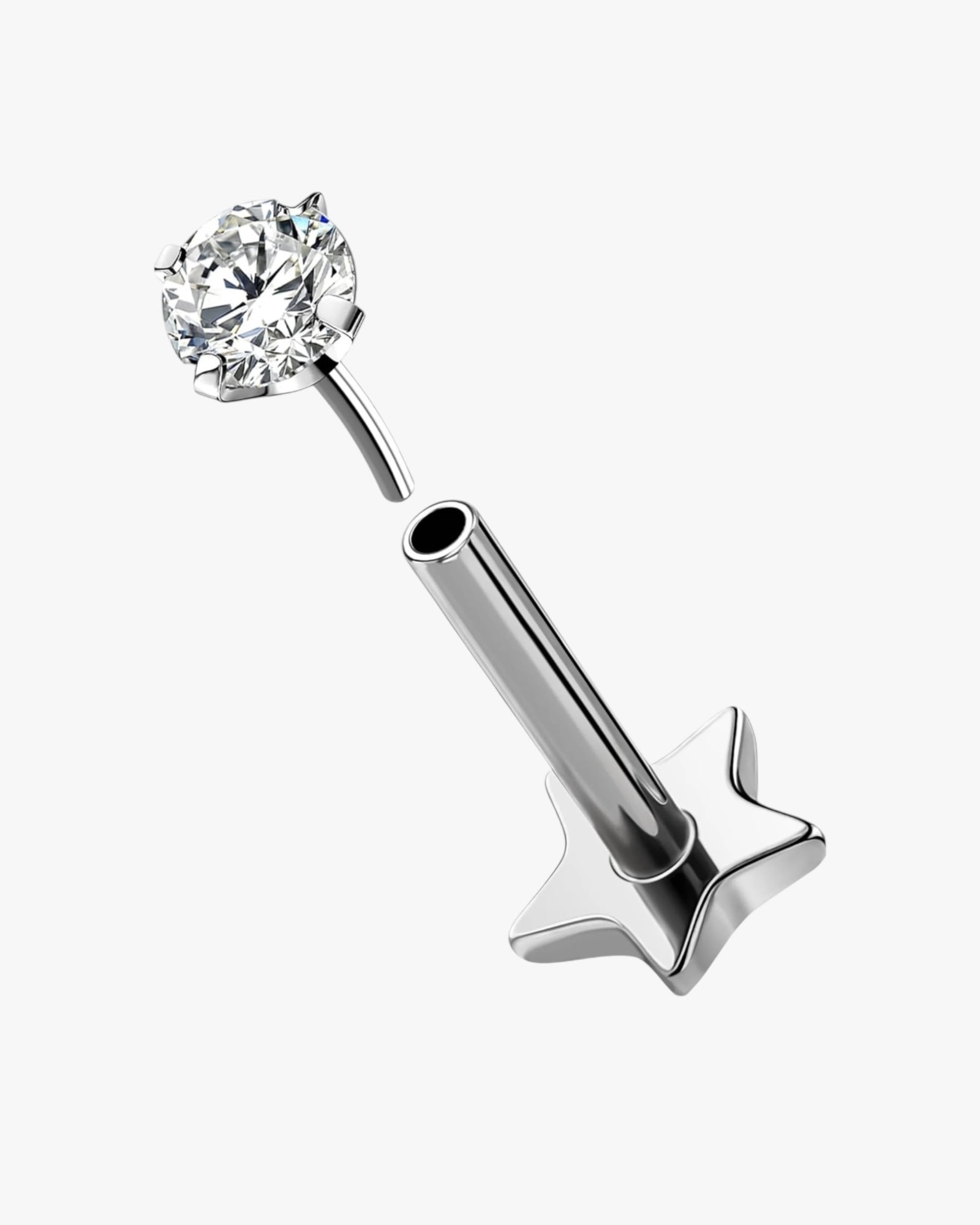 A double-headed stud piercing with a shiny metallic finish and a clear, multicolored gemstone on one of the heads.