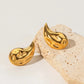 "Image: Gold drop earrings elegantly displayed on a stone surface."