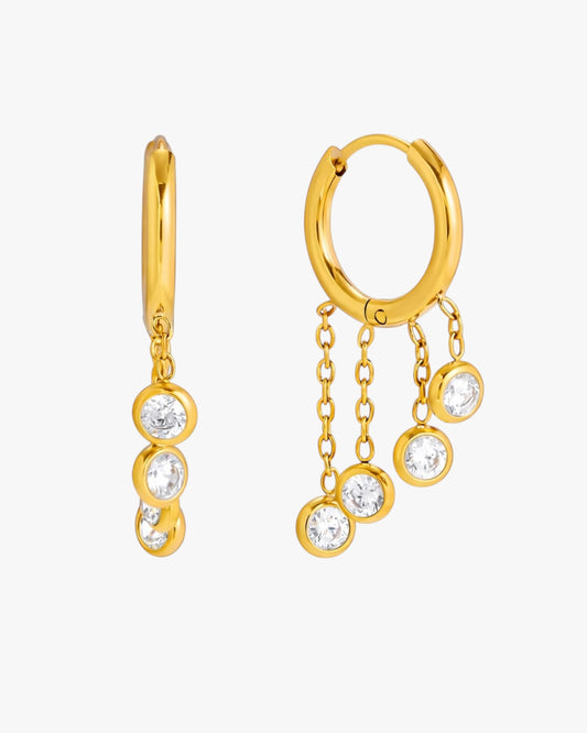 Gold hoop earrings with dangling gemstones on a white background