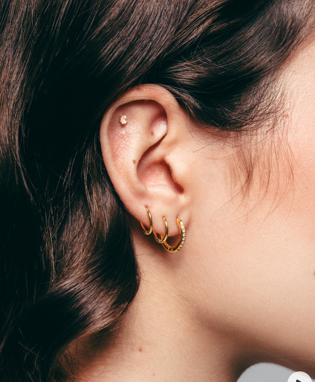 Gold plated pavé crystal hoop earrings in ear – Bari