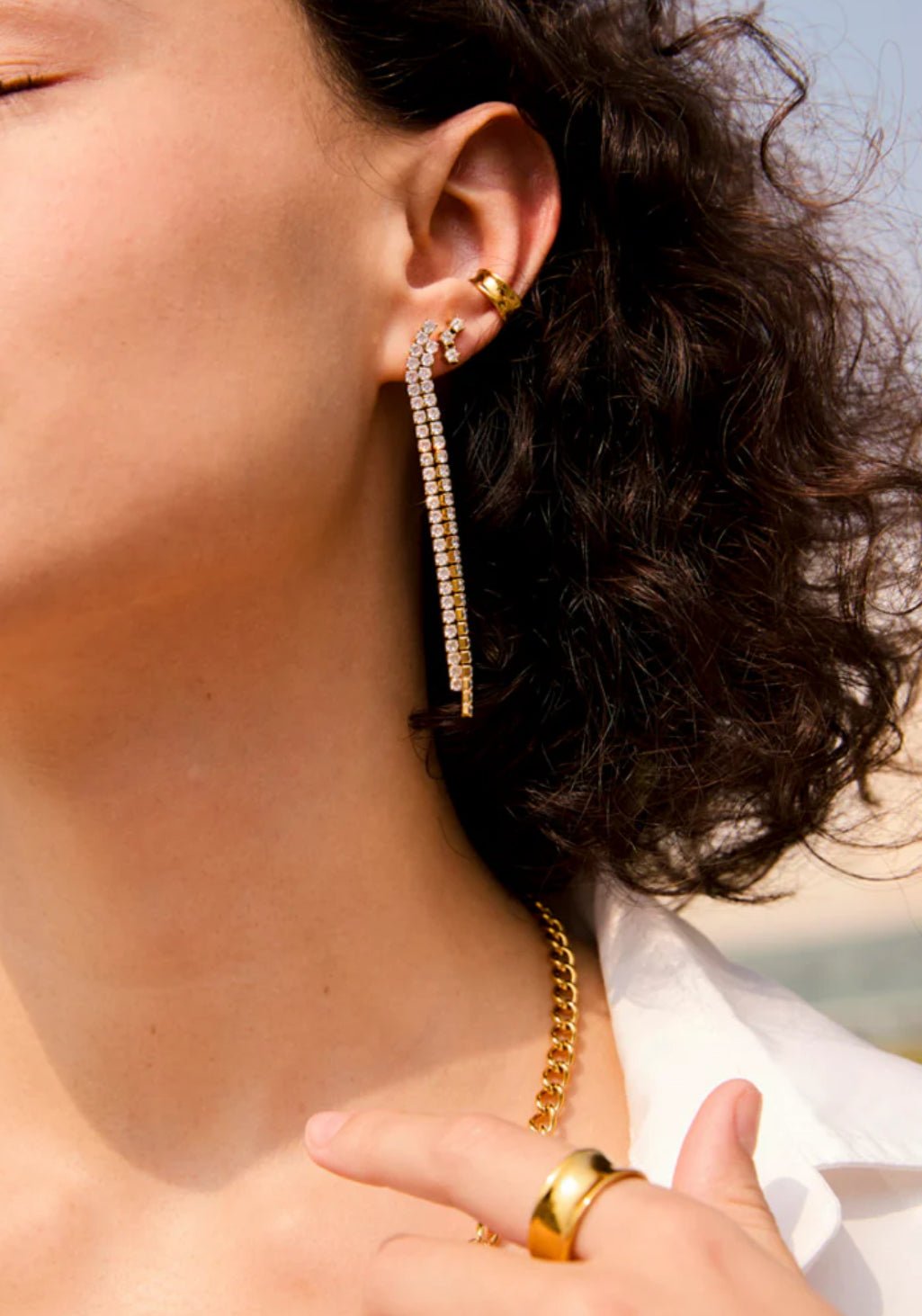 Gold double crystal stud earrings worn in ear close-up
