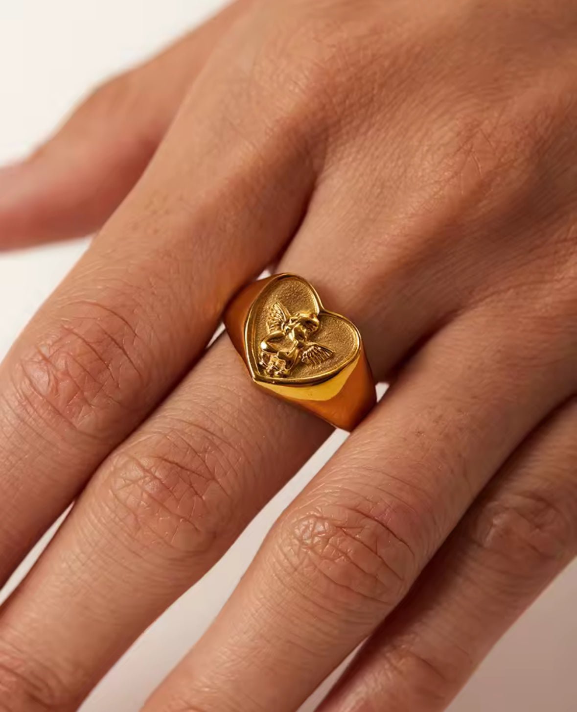 Gold plated angel cherub heart signet ring on a finger